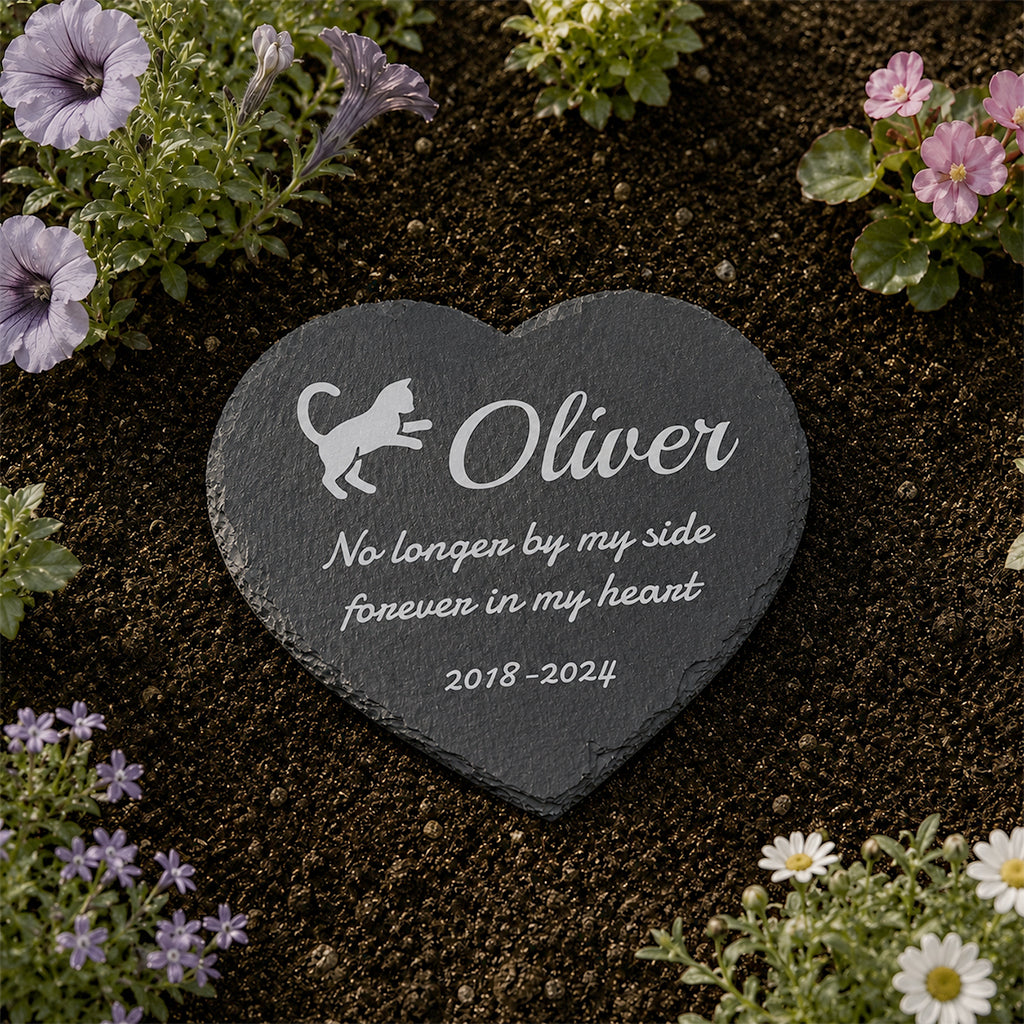 Personalized heart-shaped slate cat memorial stone with engraved cat name and dates in a garden