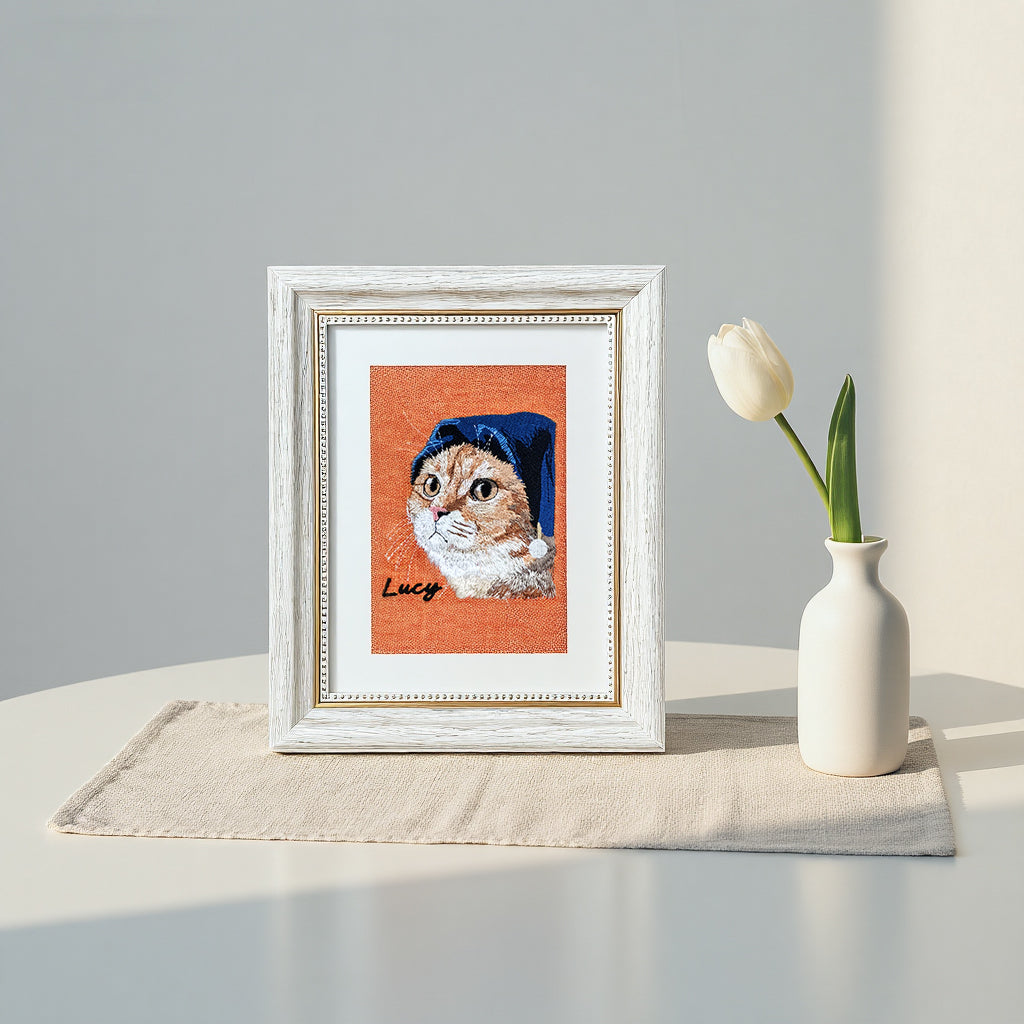 Framed pet portrait embroidery shown leaning against a shelf as a personalized pet keepsake gift