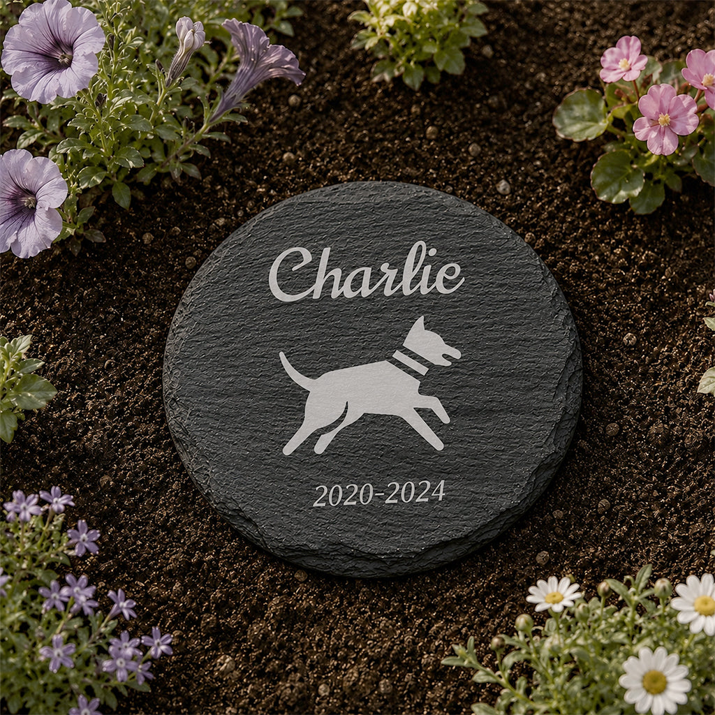 Personalized round slate dog memorial stone with engraved dog name and dates placed in a garden