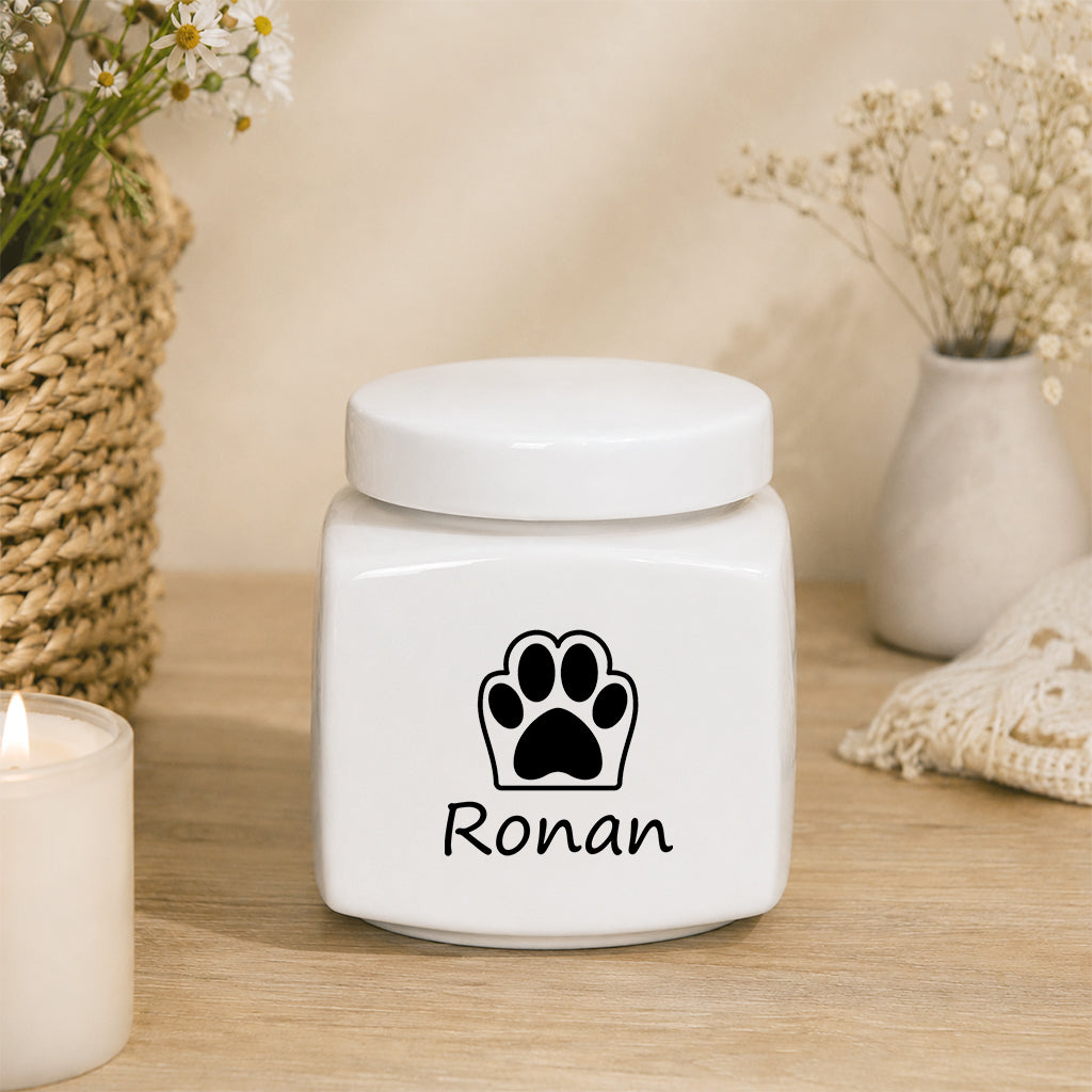 Personalized ceramic pet urn Design B with engraved pet name and paw print on white surface