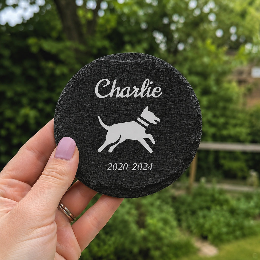 Engraved slate dog memorial stone nestled among garden plants as an outdoor remembrance marker