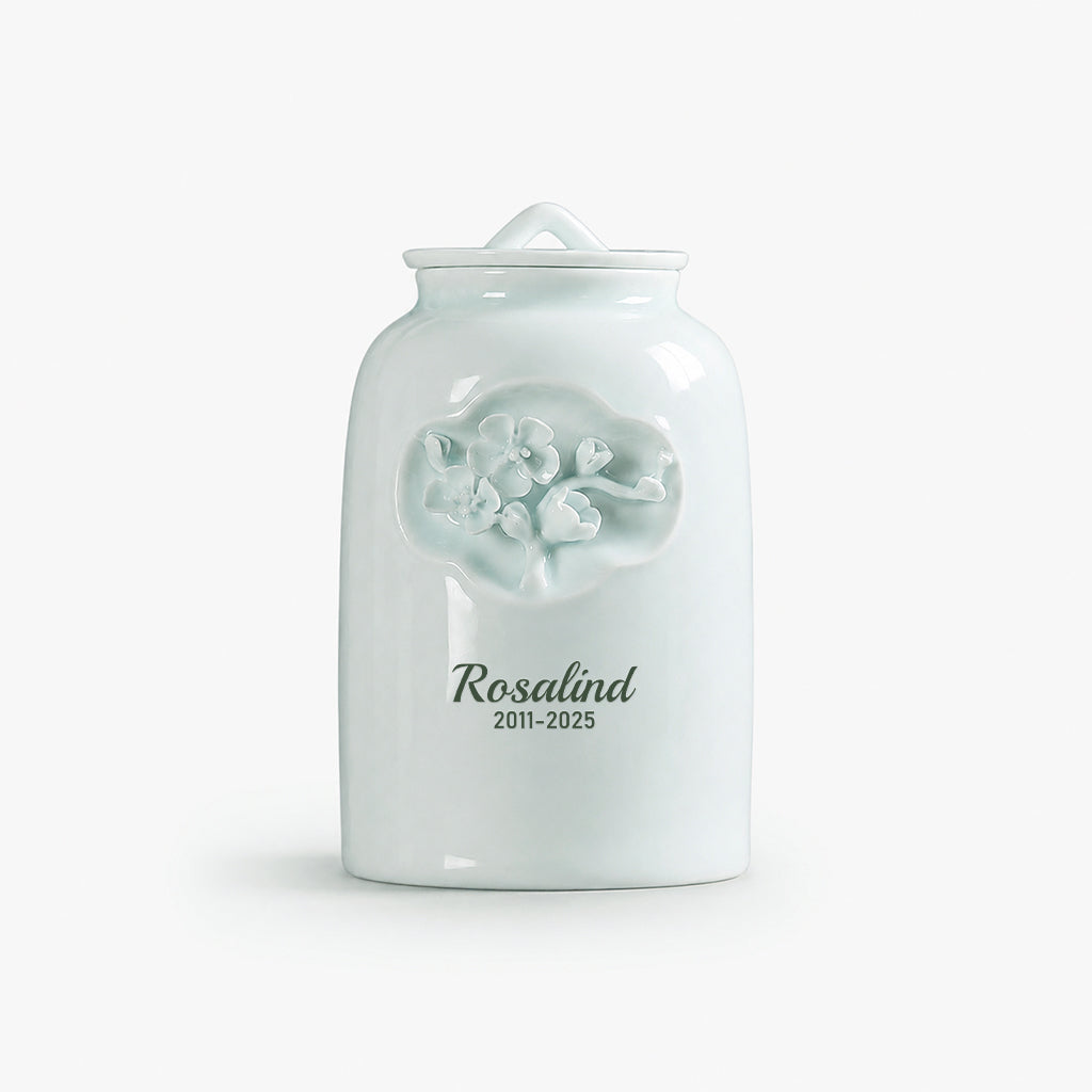 Floral ceramic pet memorial urn displayed on a wooden surface as a pet loss keepsake