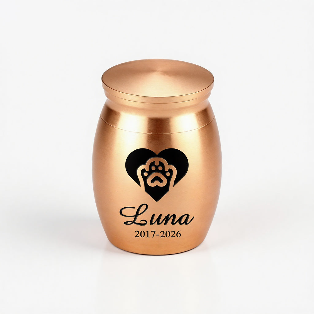 Mini pet urn with engraved name shown alongside a keepsake box and ribbon packaging