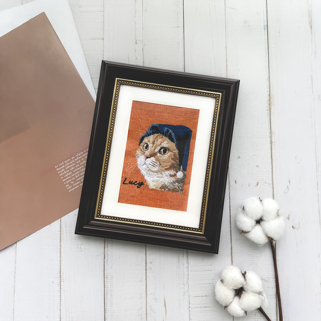 Close-up of stitched pet portrait on linen showing detailed embroidery texture and warm tones