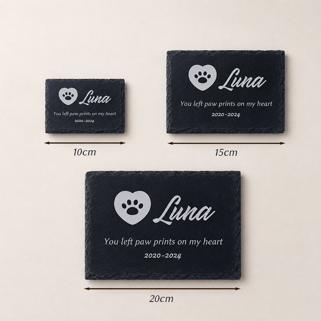 Personalized pet memorial slate plaque laid flat on grass beside garden plants