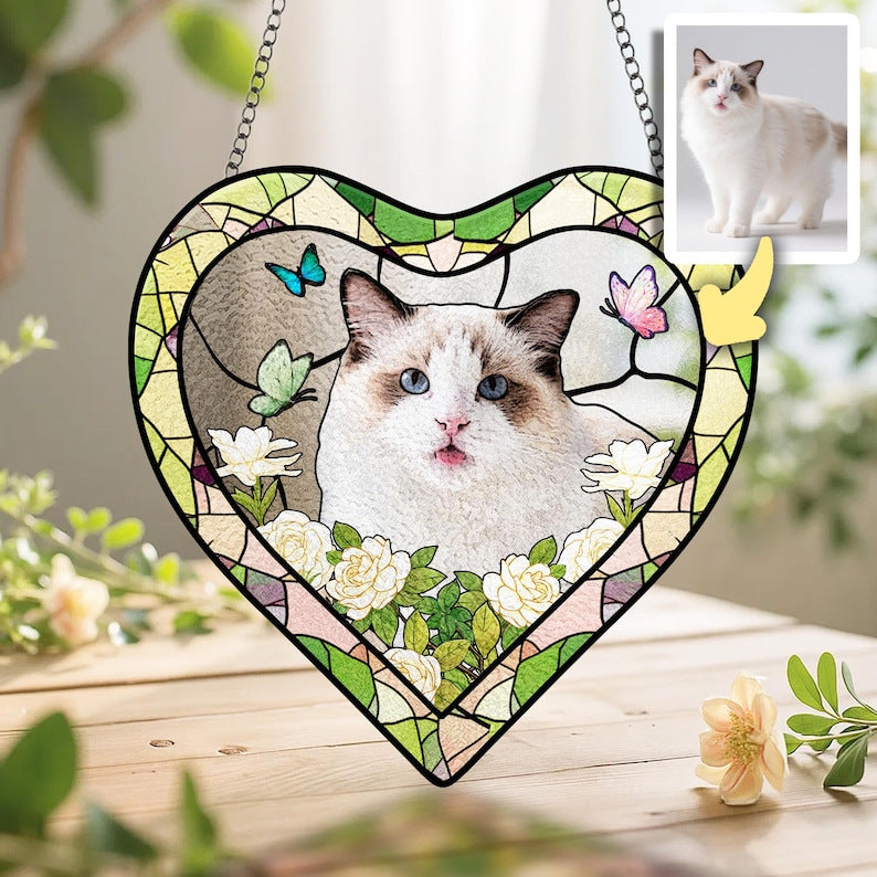Heart-shaped custom cat portrait suncatcher with floral design displayed on a wooden surface with greenery