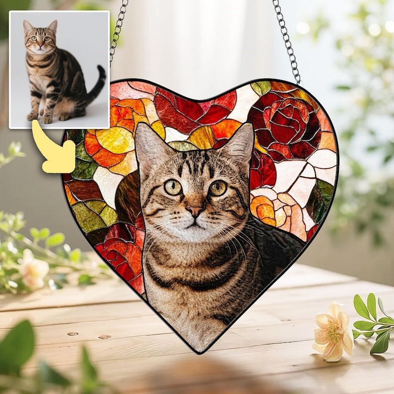 Close-up of a heart-shaped stained glass suncatcher featuring a custom cat portrait on a wooden surface