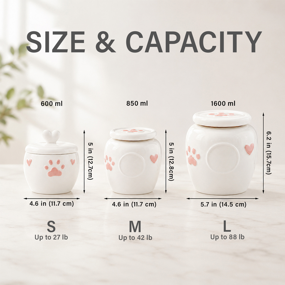 Size and capacity comparison chart for three white ceramic pet storage jars with pink paw prints and hearts, labeled S, M, and L with capacities 600 ml, 850 ml, and 1600 ml and dimensions in inches and centimeters.