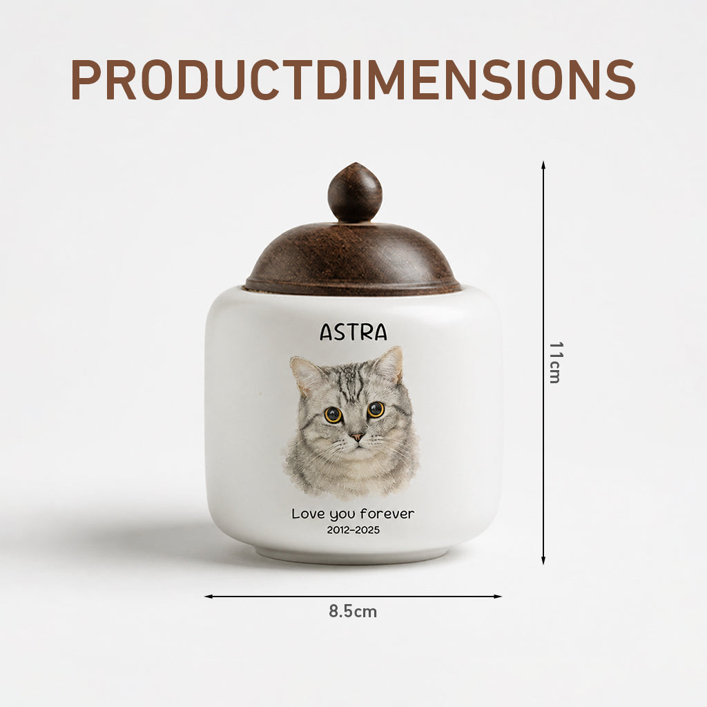 Close-up of soft watercolor cat portrait and engraved name printed on a white ceramic cremation urn