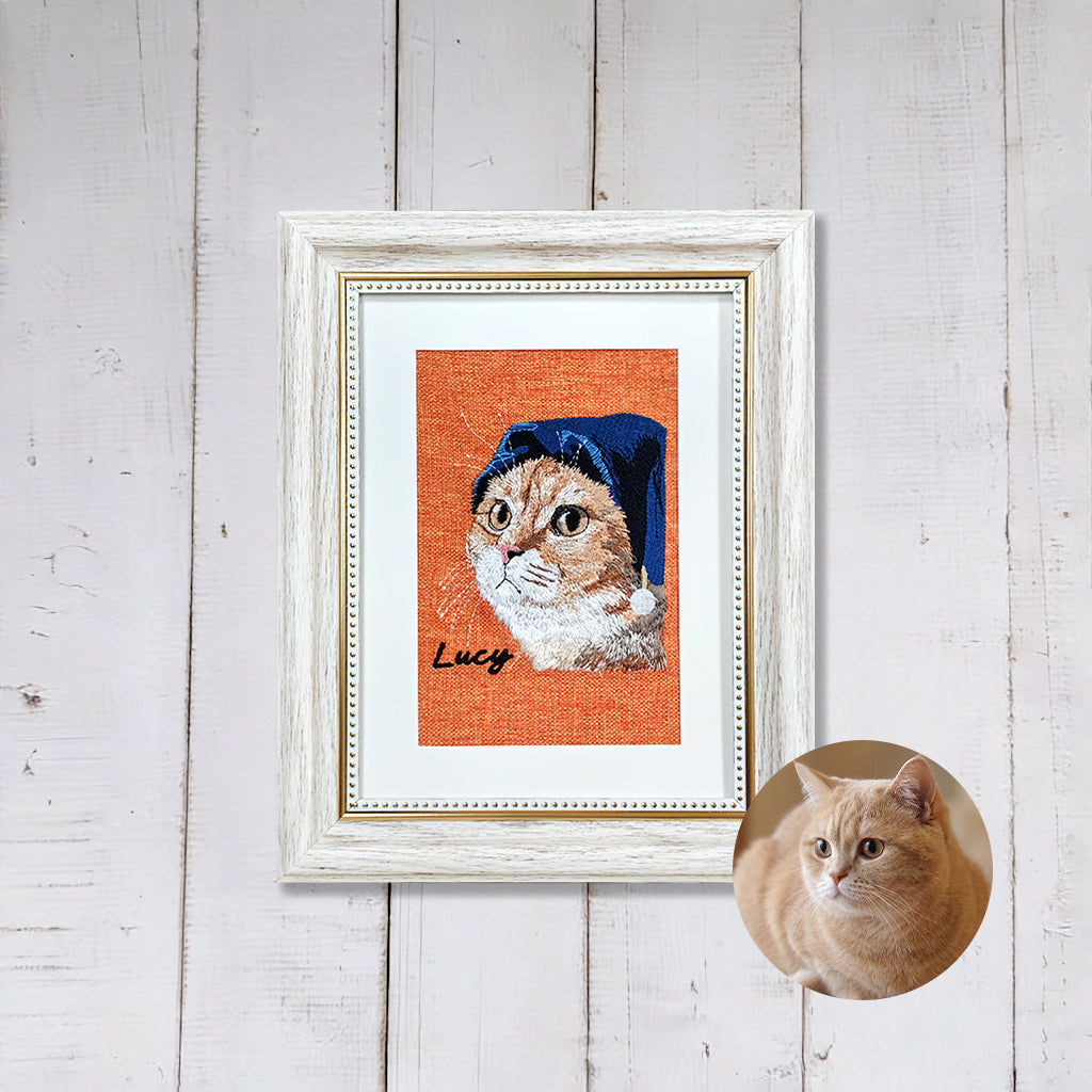 White-framed custom pet embroidery portrait displayed on a wall in a bright home setting