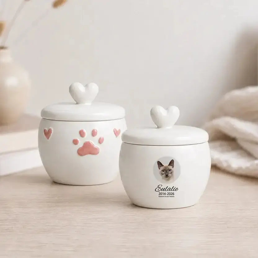 Two pink paw print cat cremation urns: a heart-lid S keepsake and an M urn with a round photo window, name and dates