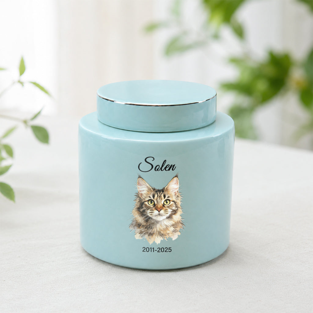 Soft teal ceramic cat cremation urn with watercolor cat portrait, name, and memorial dates on front