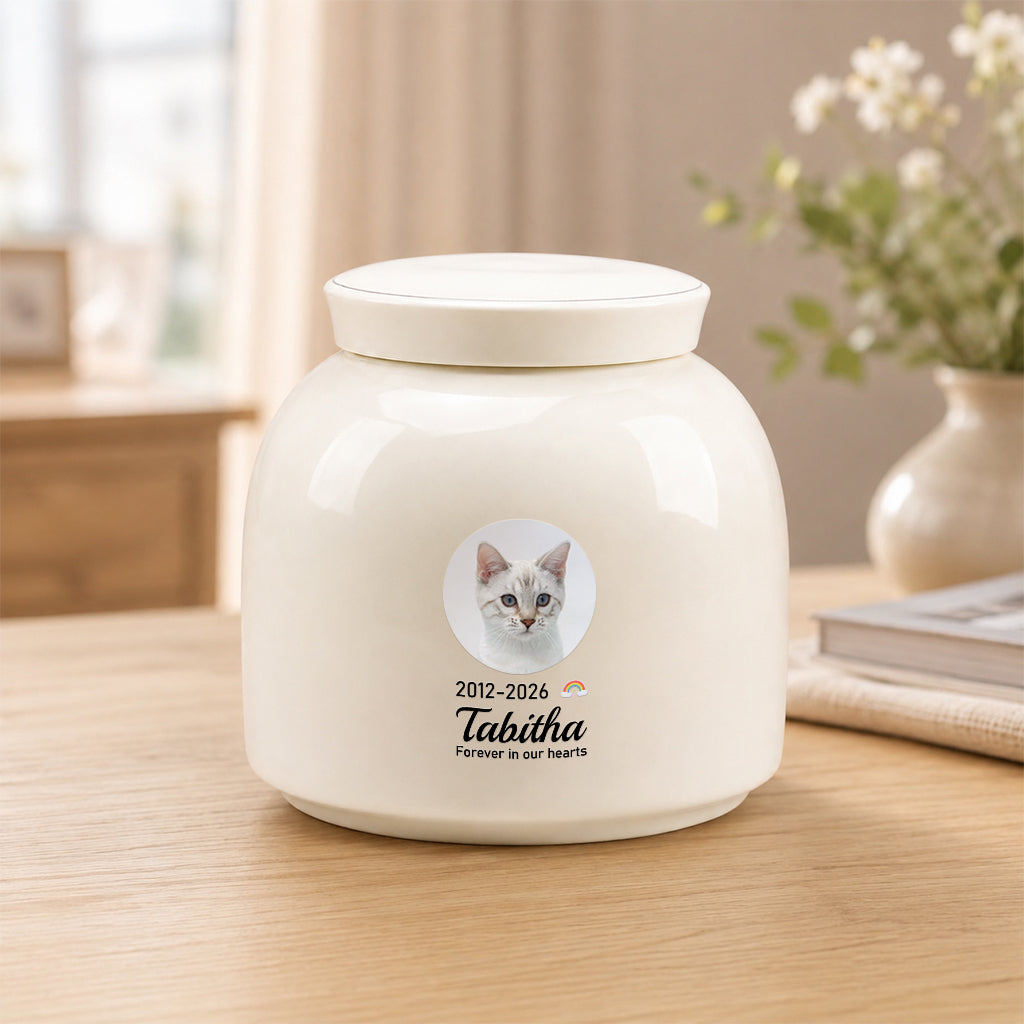 Side view of round ceramic cat memorial urn showing smooth cream finish and photo print placement