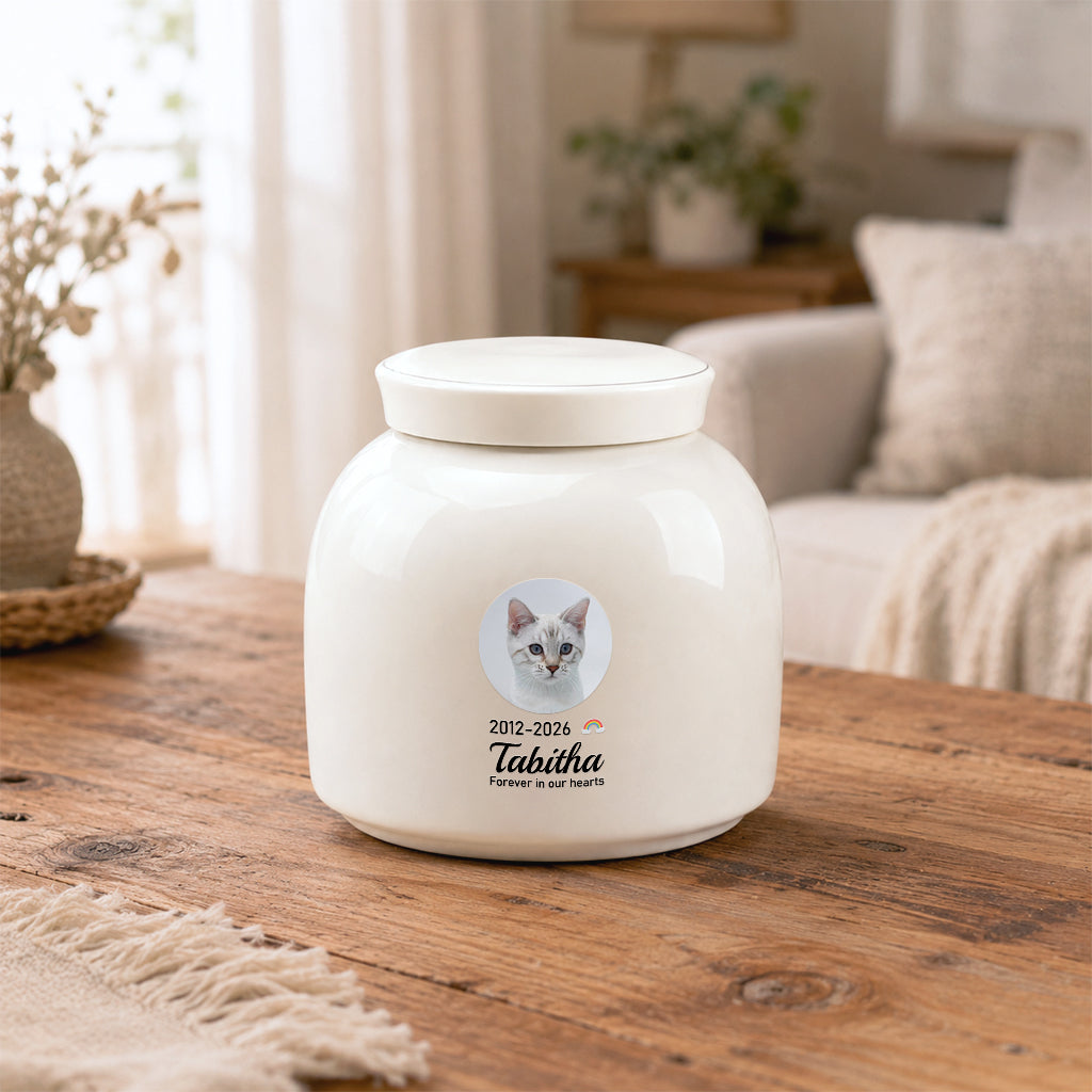 Close-up of circular cat photo, name, and dates printed on a round ceramic cremation urn