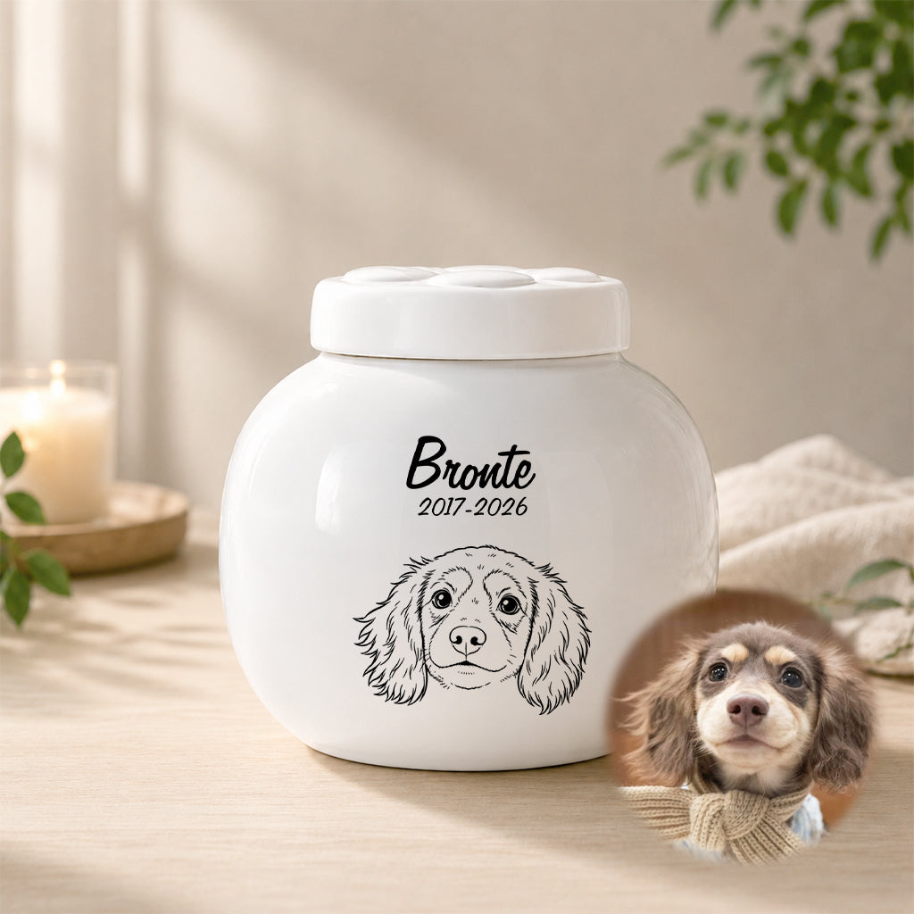Close-up of personalized dog name and memorial dates engraved on a white ceramic cremation urn