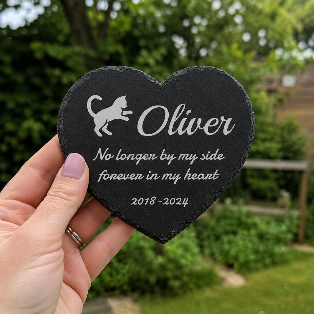 Engraved slate cat memorial stone placed among garden flowers as an outdoor remembrance marker