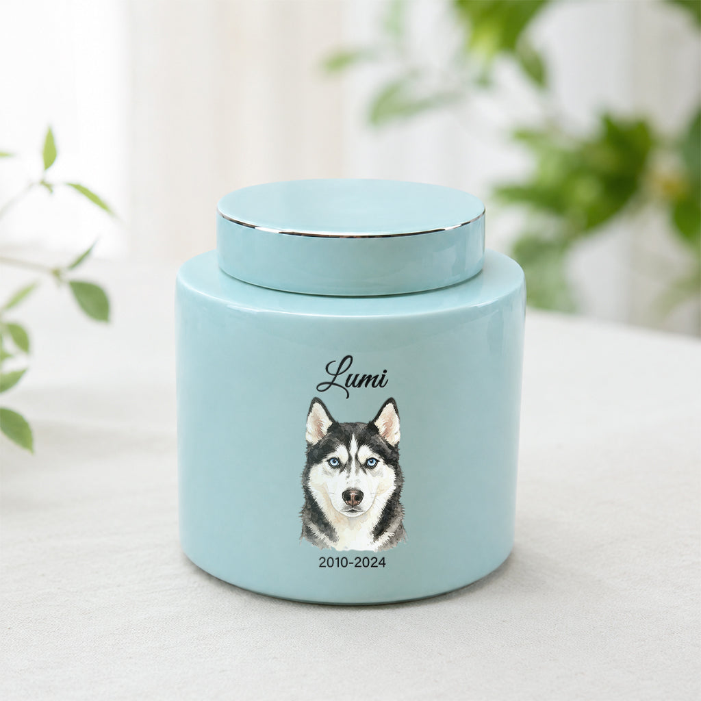 Soft teal ceramic dog cremation urn with watercolor dog portrait, name, and memorial dates on front