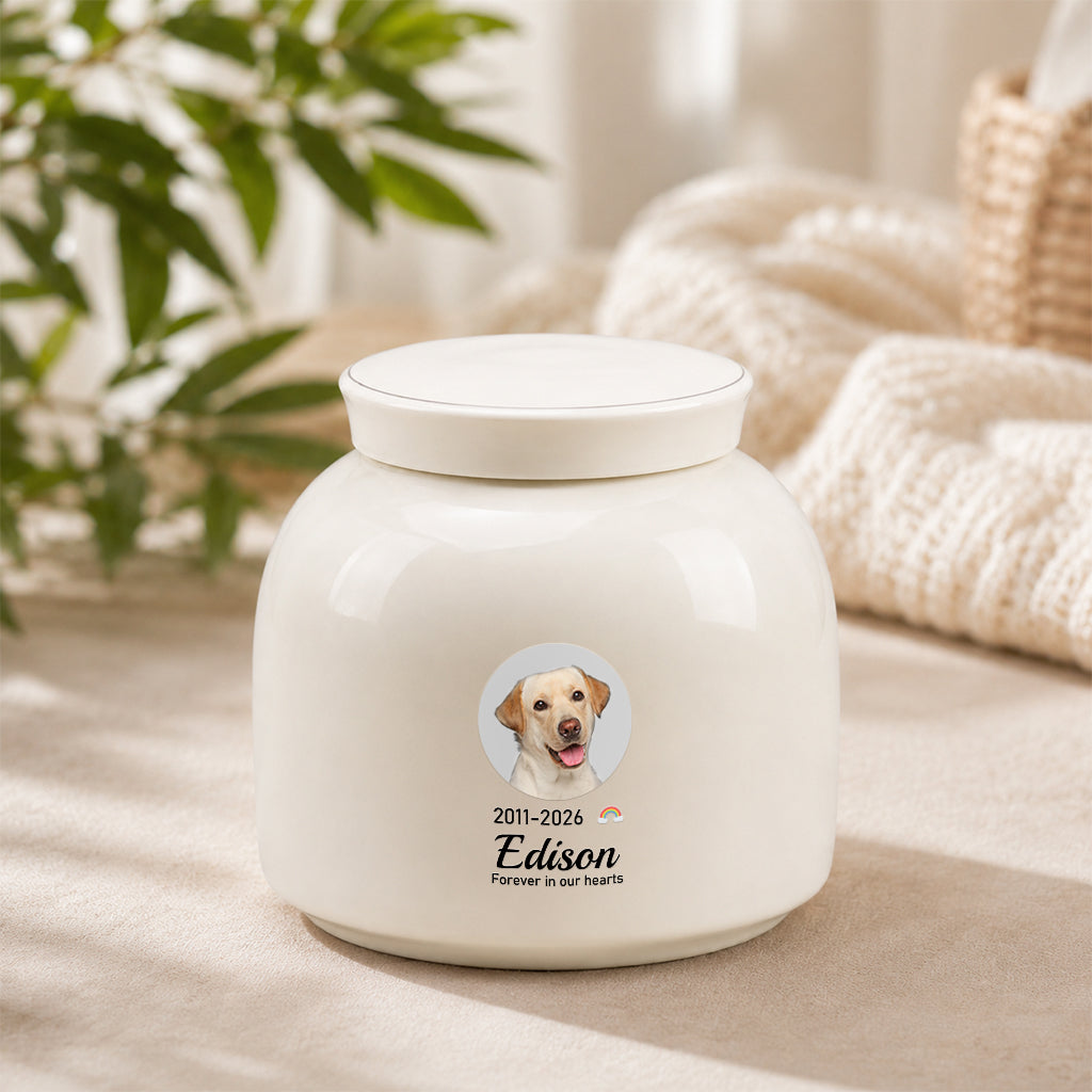 Cream-white round ceramic dog cremation urn with circular dog photo, name, and memorial dates on front