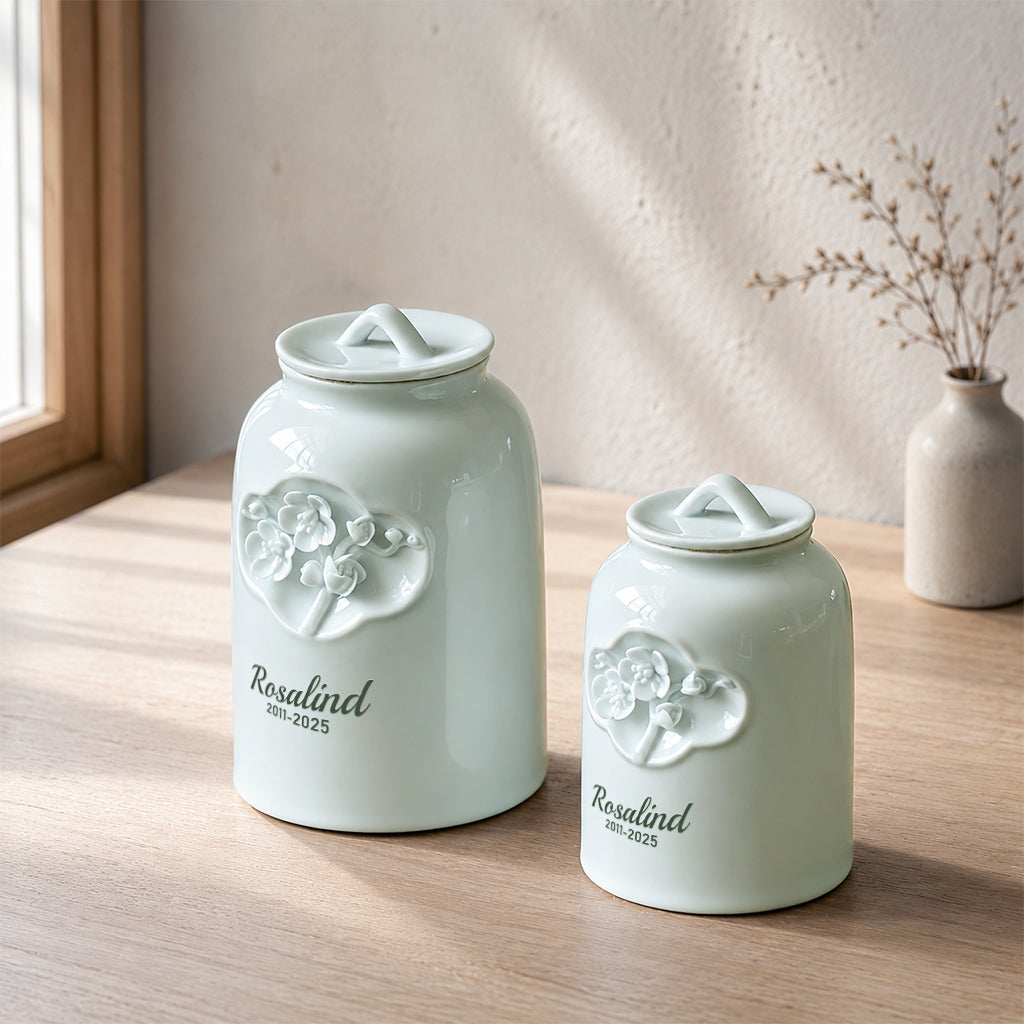 Close-up of raised floral pattern and engraved pet name on a celadon ceramic cremation urn