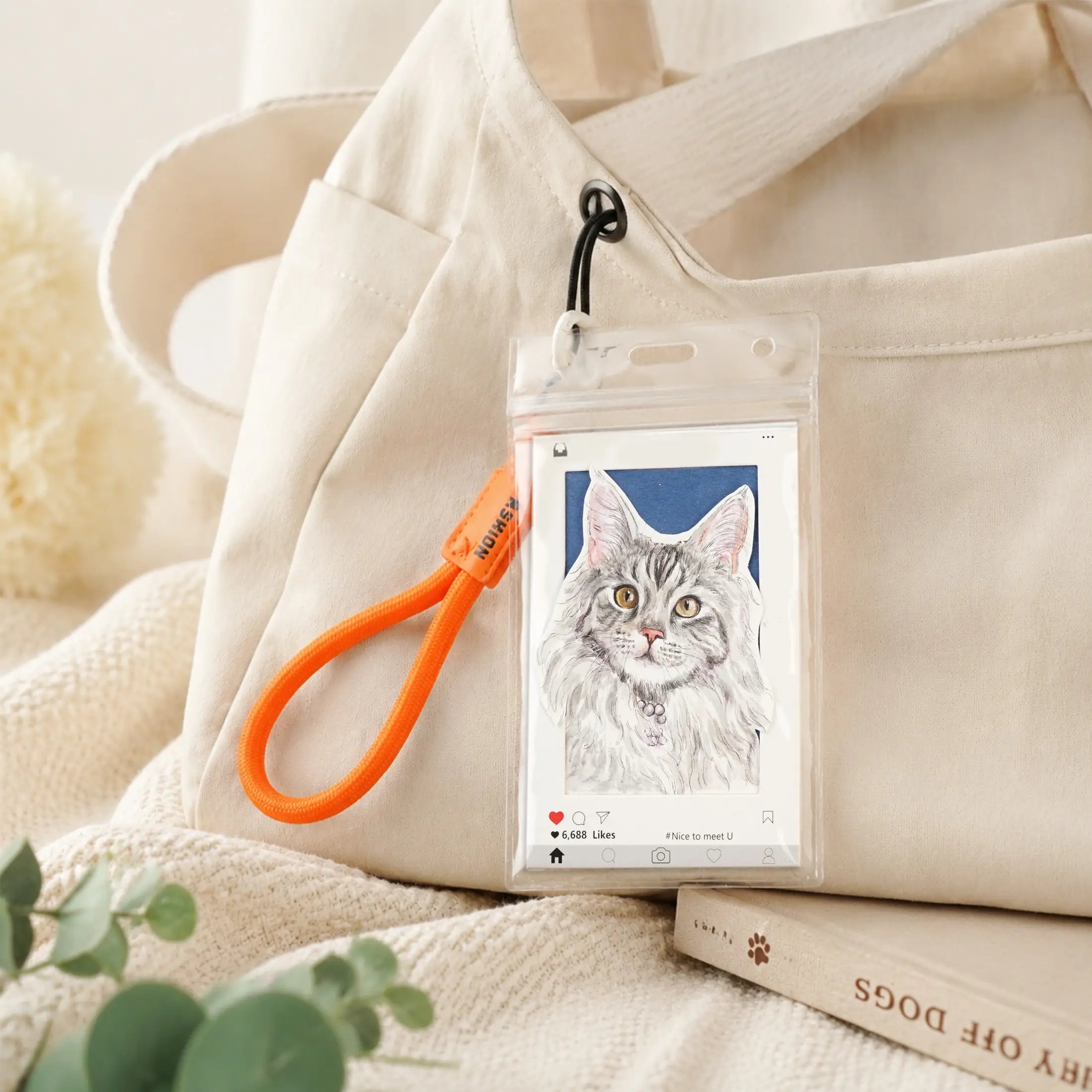 Hand-painted cat portrait keychain clipped to a canvas tote bag with an orange wrist strap