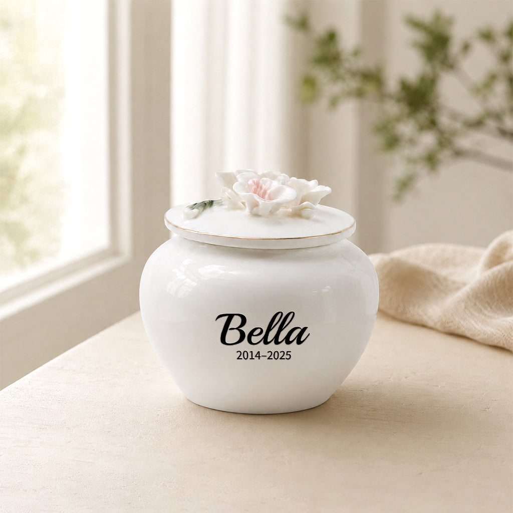 White ceramic pet keepsake urn with sculpted peach blossom floral lid and engraved pet name and dates