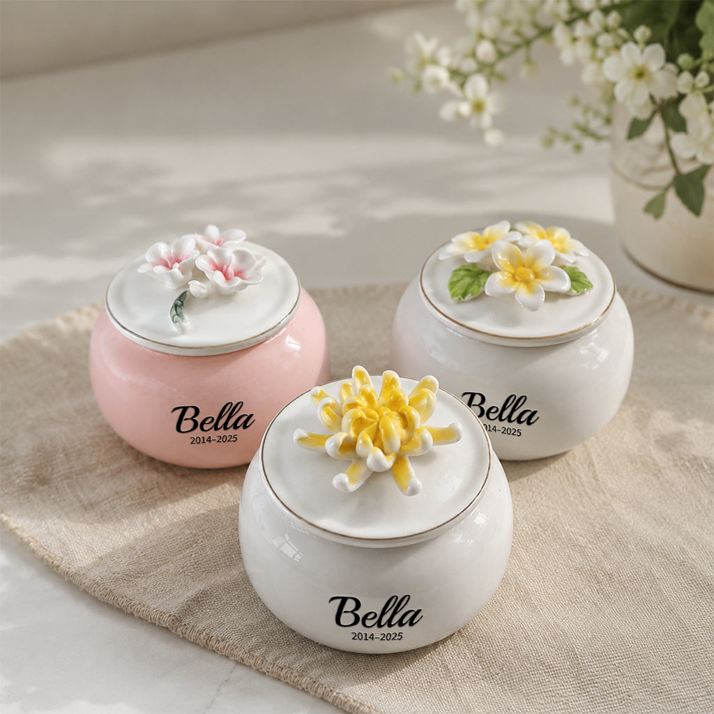 Close-up of sculpted floral lid on a round white porcelain pet keepsake urn with engraved name detail